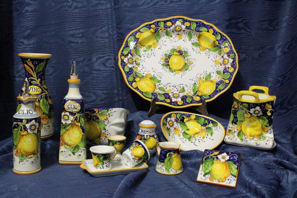 some objects of the collection Limoni on blue background ceramics Borgioli, handmade ceramics made and decorated by hand ; there are different olive oil bottles, a big tray, an utensil holder sac and many other beautiful objects.